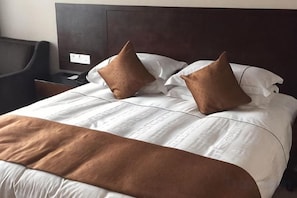 Un letto rifatto con una coperta marrone e due cuscini.