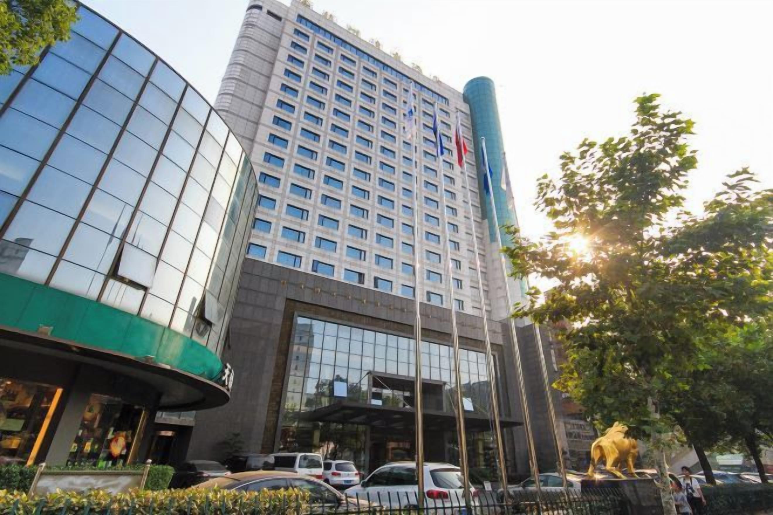 Un hotel de varios pisos con una entrada destacada, un amplio frente de vidrio y una estatua al frente.