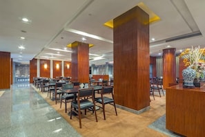 Una hall d'albergo con una lunga reception, diverse zone salotto e un design moderno.