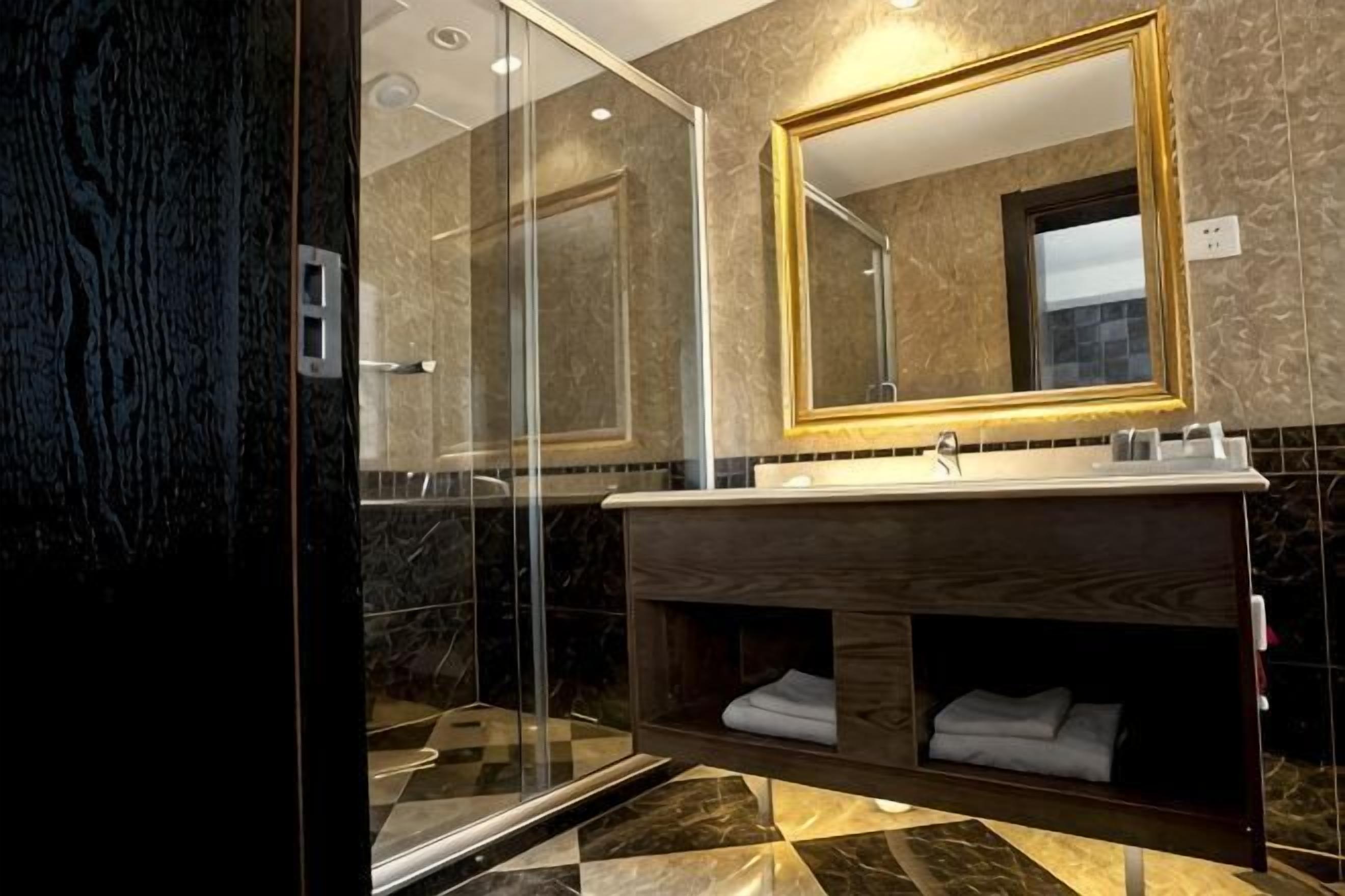 A modern bathroom with a glass shower enclosure, a wooden vanity, and a large mirror.