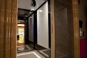 A hotel corridor with a reception area visible in the background. - Reese Hotel (Beijing)