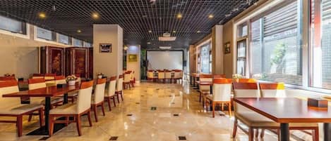 Un restaurante con varias mesas y sillas, piso de baldosas y techo con diseño de cuadrícula.