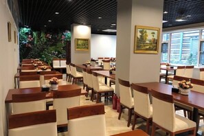 A restaurant interior with multiple dining tables and chairs, a decorative wall with a painting, and a large window providing natural light. - Reese Hotel (Beijing)