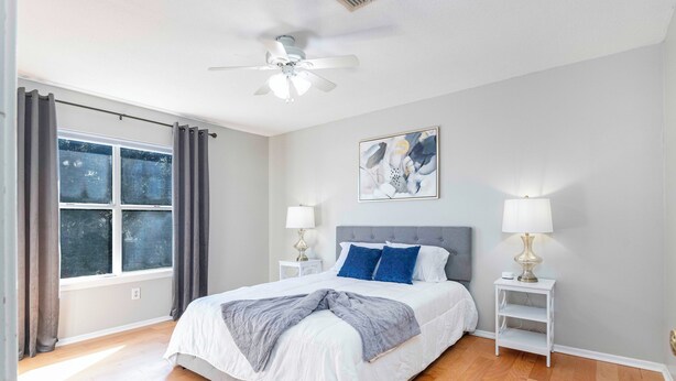 A bedroom with a bed, two bedside tables with lamps, a ceiling fan, a window with curtains, and a wall-mounted abstract art piece. - Charming 2-bedroom, queen-bed, townhome in the center of Lafayette with AC, WiFi (Lafayette)