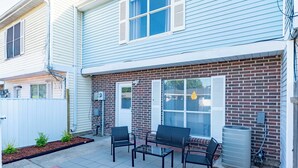 A patio with a table and chairs, a brick wall, and a white fence. - Charming 2-bedroom, queen-bed, townhome in the center of Lafayette with AC, WiFi (Lafayette)