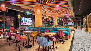 A vibrant indoor space with colorful ceiling patterns, seating areas, and tables.