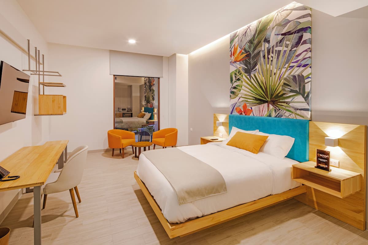 Une chambre d’hôtel moderne avec un grand lit, un bureau et deux chaises.