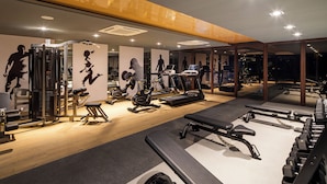 A modern gym with various exercise equipment, including treadmills, elliptical machines, and weight stations.