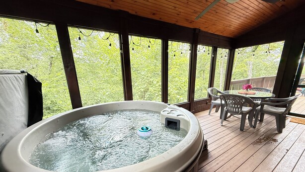 A hot tub on a wooden deck with a table and chairs nearby. - Look NO Further - Hot Tub, 6 miles from Cades Cove (Townsend)