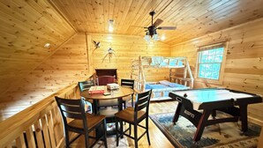 A cozy cabin with a wooden interior, a round dining table, a pool table, and a bunk bed. - Look NO Further - Hot Tub, 6 miles from Cades Cove (Townsend)