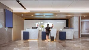 A reception desk with two staff members, a marble floor, and a world map on the wall. - Kyriad Hotel (Mangshi Plaza) (Mangshi)