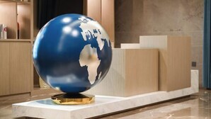 A globe sculpture on a pedestal in a lobby area with a marble floor and wooden paneling. - Kyriad Hotel (Mangshi Plaza) (Mangshi)
