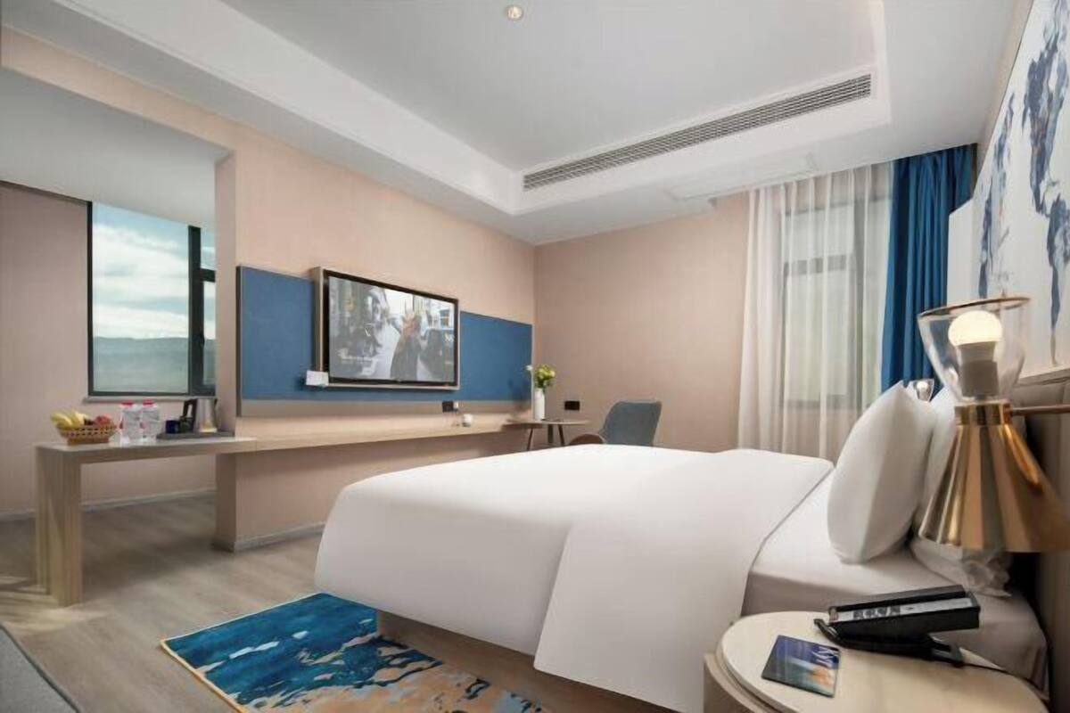 Hotellihuone, jossa on suuri sänky, työpöytä, televisio ja näkymä ulos.