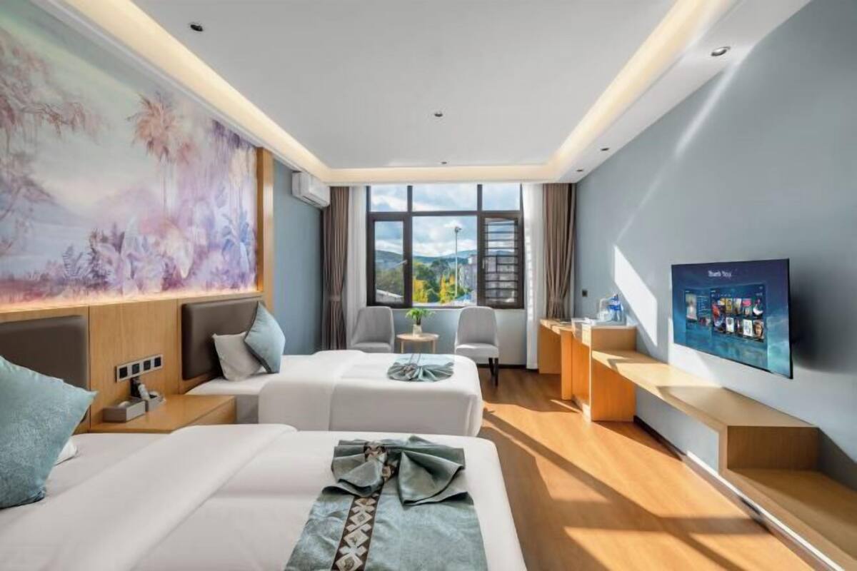 Une chambre d’hôtel moderne avec deux lits, une grande fenêtre, un téléviseur à écran plat et un tableau au mur.