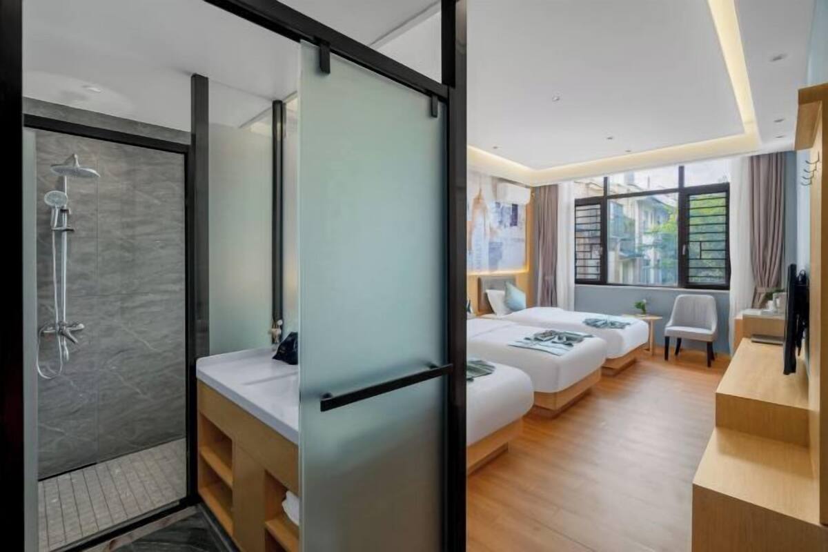 Une chambre d’hôtel moderne équipée d’une douche, de deux lits, d’un bureau et d’une grande fenêtre.