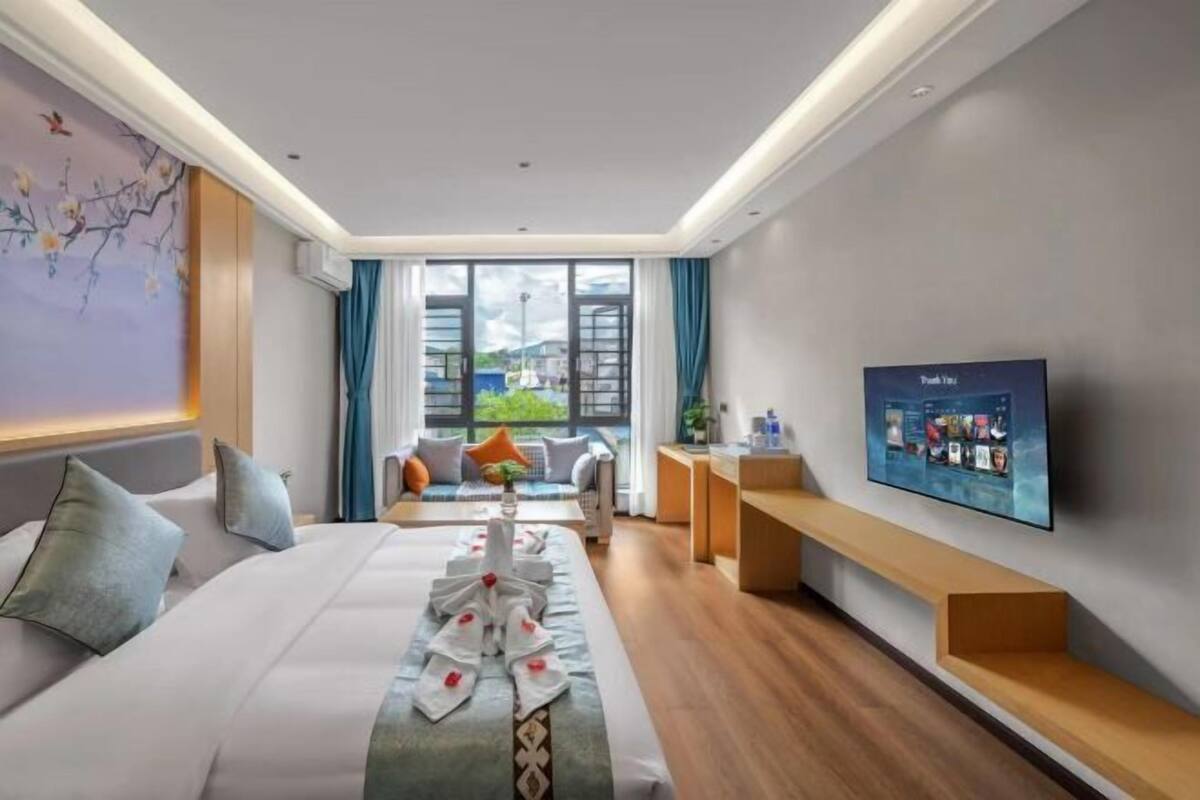 Une chambre d’hôtel moderne équipée d’un lit, d’une télévision, d’un bureau et offrant une vue sur l’extérieur.