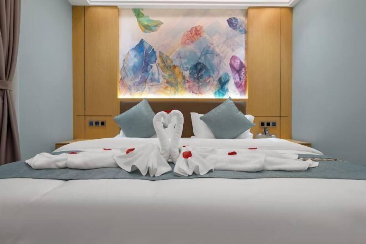 Une chambre d’hôtel avec un lit, une œuvre d’art accrochée au mur et une armoire en bois.