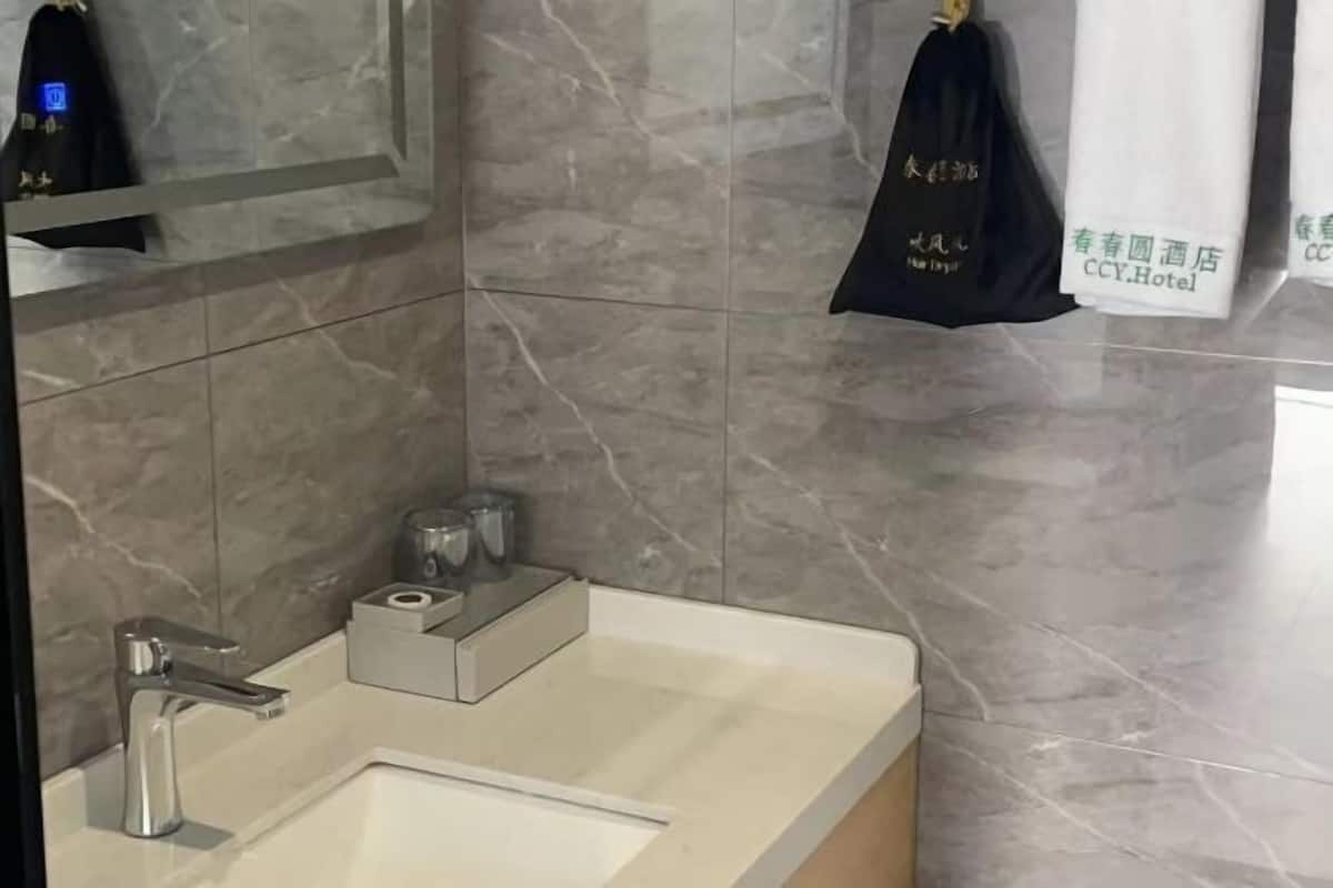 Ein Badezimmer mit einem modernen Waschbecken, Spiegel und Handtuchhalter.