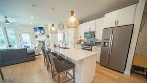 Una cocina moderna con una isla central, electrodomésticos de acero inoxidable y un refrigerador grande.