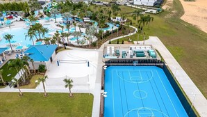 An aerial view of a resort with multiple swimming pools, a basketball court, and surrounding greenery. - LUXURY LIVES 8 BEDROOM 6 BATHS REAR END HOME WINDSOR CAY |Complimentary Pool&BBQ (Clermont)