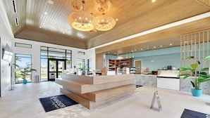A modern hotel lobby with a wooden reception desk, large windows, and a kitchen area visible through the glass. - LUXURY LIVES 8 BEDROOM 6 BATHS REAR END HOME WINDSOR CAY |Complimentary Pool&BBQ (Clermont)
