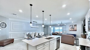 A modern kitchen with a central island, white cabinetry, and pendant lighting.