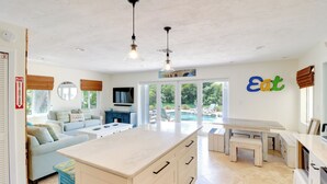 A spacious kitchen with a large island, a dining area, and a living room with a sofa. - Walk to Beach: Waterfront Home in Marathon! (Marathon)