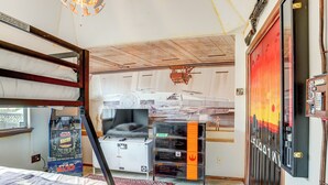 Um quarto com beliches, um jogo de fliperama de Star Wars, um guarda-roupa com tema Star Wars e um pôster de Star Wars.