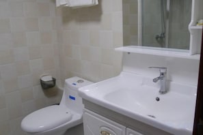 A bathroom with a toilet, sink, and mirror. - Qingyou Hotel (Yueqing)