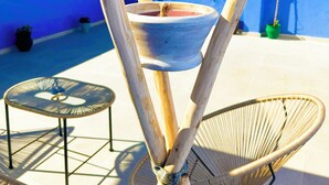 Una terraza en la azotea con mesa y sillas, un muro azul y vistas al campo.