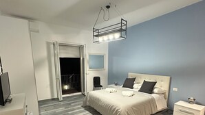 A modern bedroom with a bed, bedside tables, a desk, and a green chair. - Guesthouse with direct access to the beach (Portici)