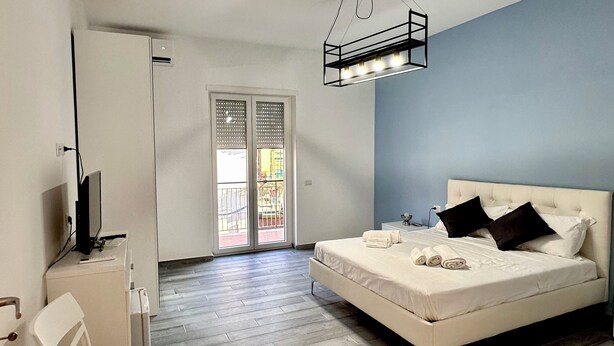 A bedroom with a bed, a desk, a chair, and a large window. - Guesthouse with direct access to the beach (Portici)