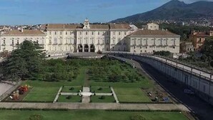 A large, historic building with a symmetrical facade, a central courtyard with a fountain, and a mountain in the background. - Guesthouse with direct access to the beach (Portici)