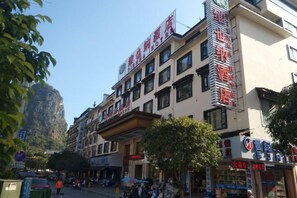 A multi-story building with commercial establishments on the ground floor, including a pharmacy and a restaurant. - Vienna Hotel (Yangshuo West Street Qianguqing Branch) (Yangshuo)