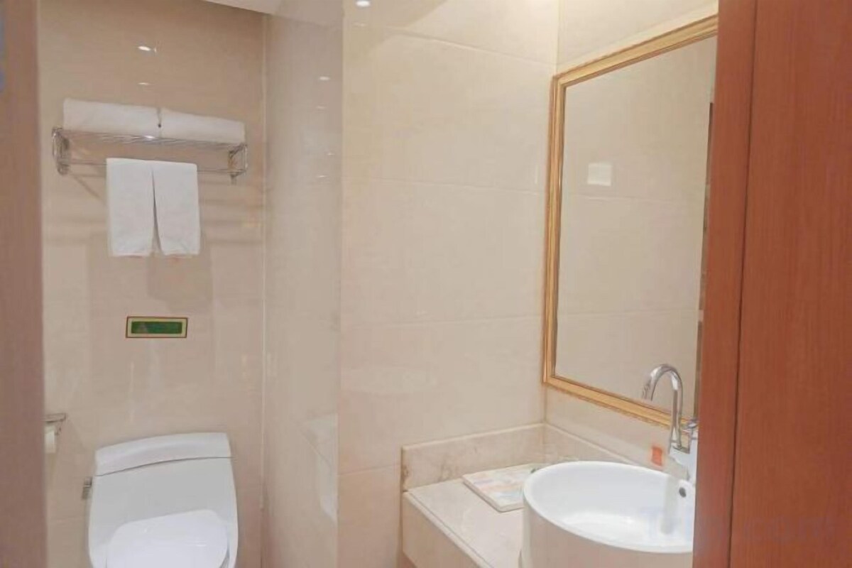 A bathroom with a toilet, sink, mirror, and towel rack.