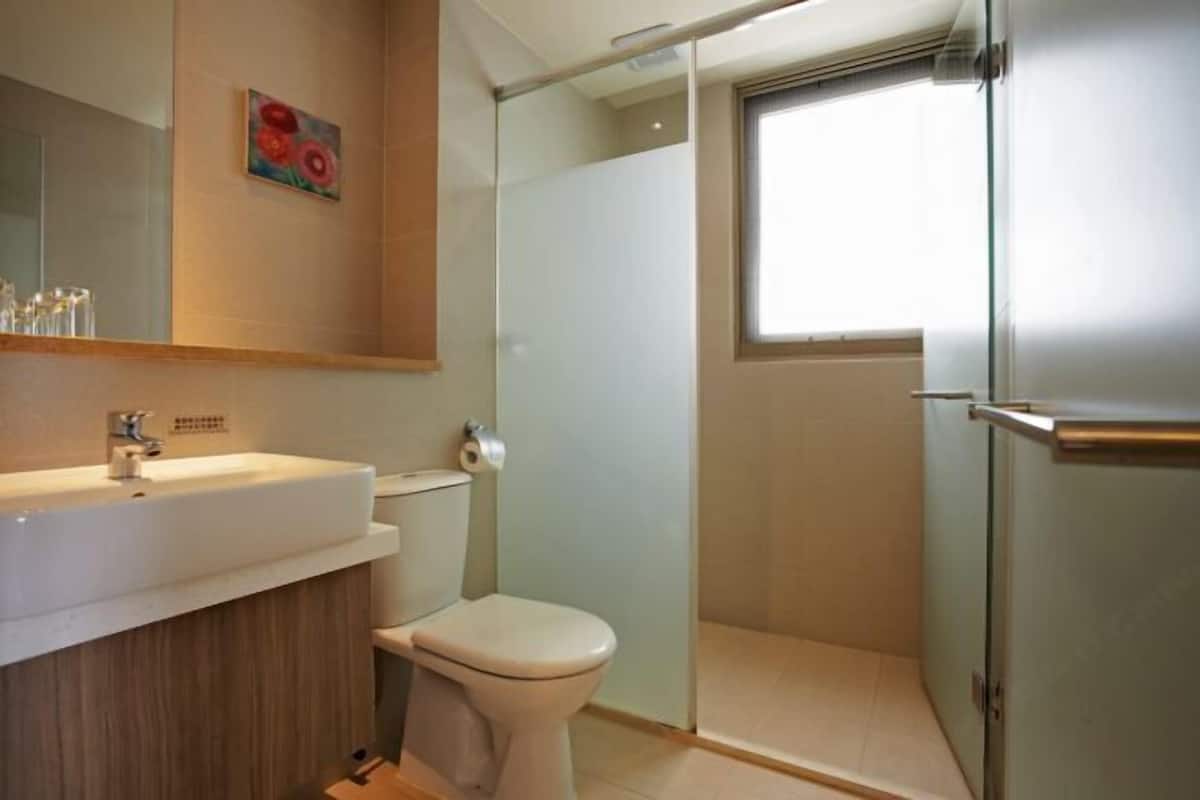 A modern bathroom with a glass shower enclosure, a toilet, and a sink with a mirror above.