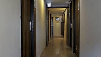 A hotel corridor with wooden doors, a wooden floor, and a ceiling with recessed lighting.