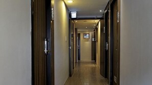 A hotel hallway with wooden doors, a wooden floor, and a ceiling with recessed lighting. - Micasa Hotel (Taichung)