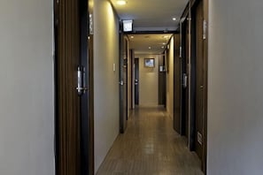 A hotel hallway with wooden doors, a wooden floor, and a ceiling with recessed lighting. - Micasa Hotel (Taichung)