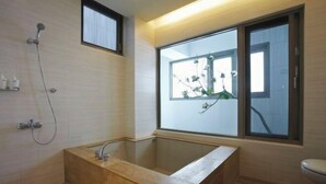 A modern bathroom with a glass-enclosed bathtub, a window, and a shower. - Micasa Hotel (Taichung)