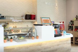 A cafe counter with a menu board, a coffee machine, and a display case with items. - Micasa Hotel (Taichung)