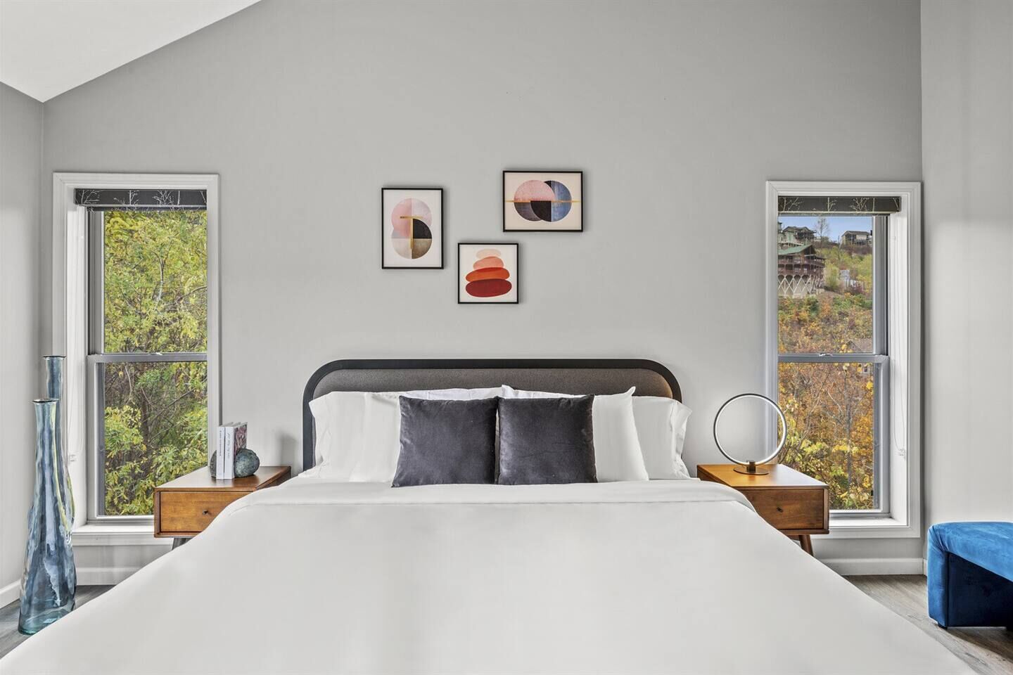 A bedroom with a large bed, two bedside tables, and three framed artworks on the wall.