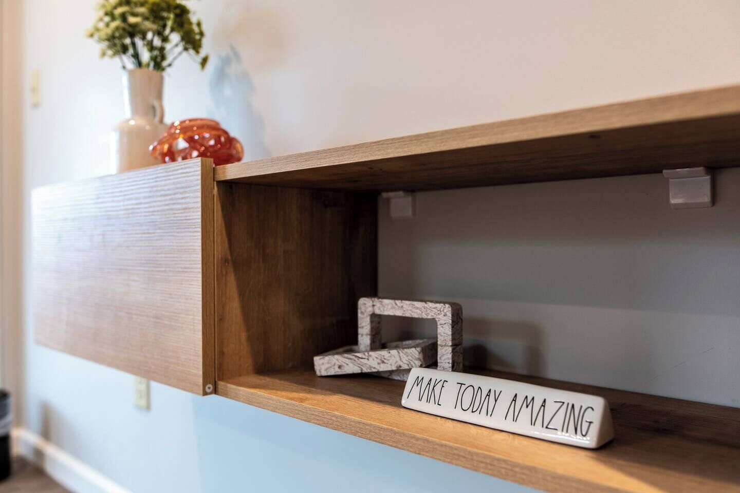 Uma prateleira de madeira com uma placa de inspiração dizendo "MAKE TODAY AMAZING".