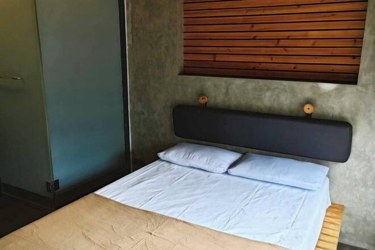 A bed with a headboard, a wooden wall panel, and a door.