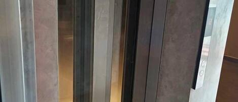 En dörr med ett metallhandtag och en glasruta, troligen leder den in till ett rum eller en hall.