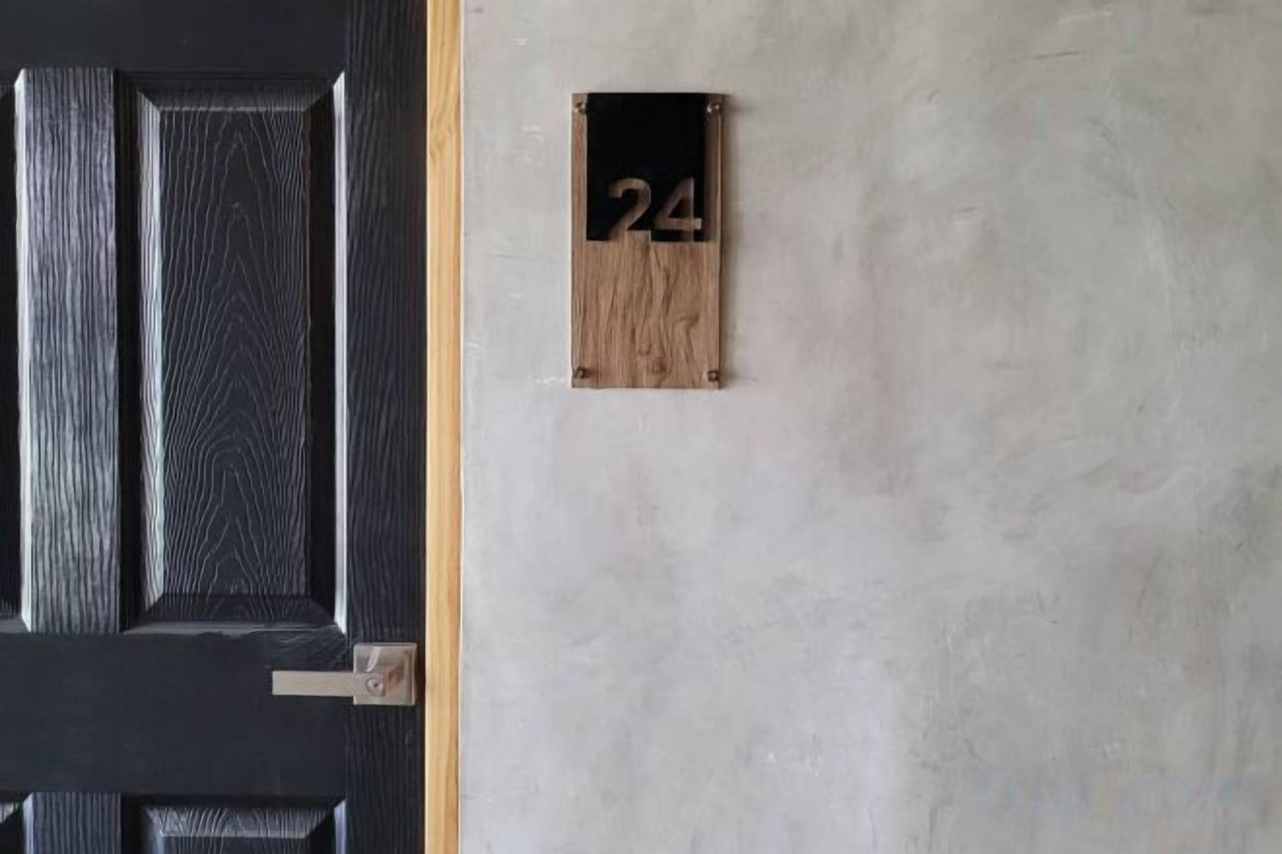 Uma porta preta com uma placa de madeira mostrando o número 24.