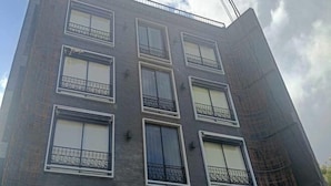 A multi-story building with a brick facade, multiple balconies with metal railings, and a partially visible construction area on the right. - Ramos Hello Stay Cebu (Cebu City)