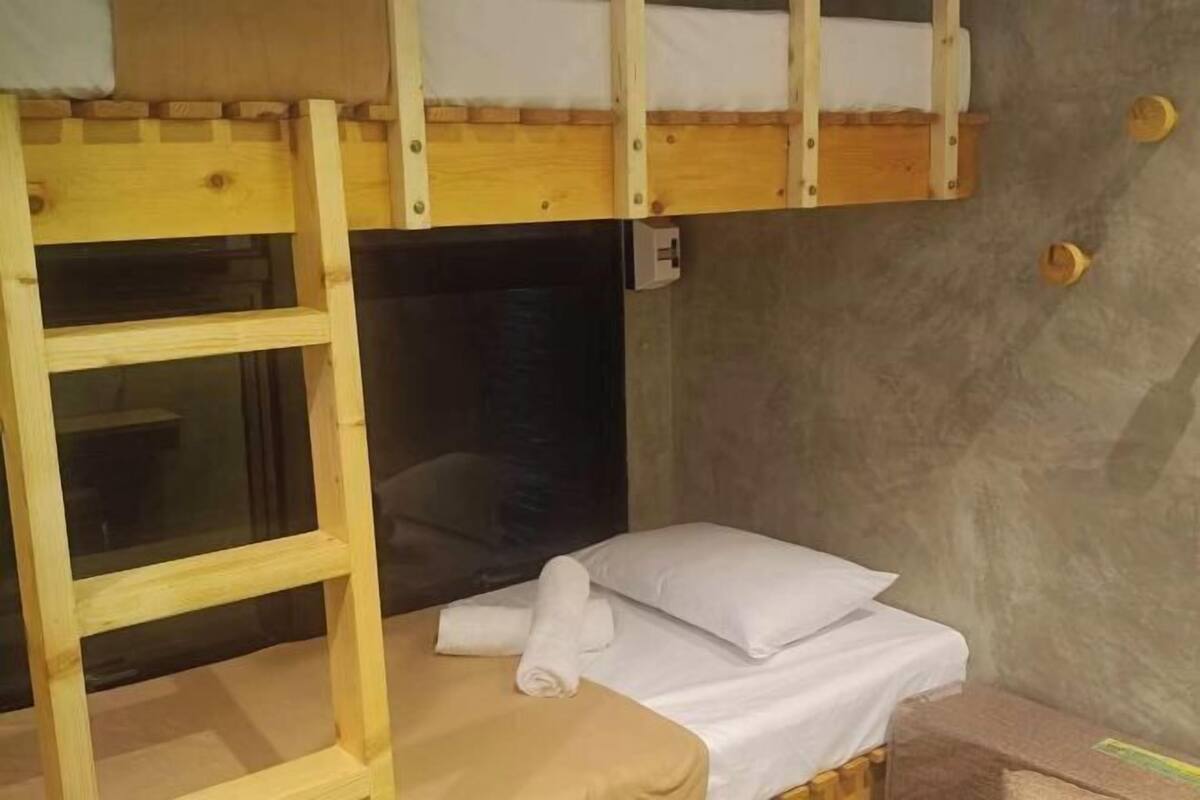 A bunk bed with a ladder, a small desk, and a window.