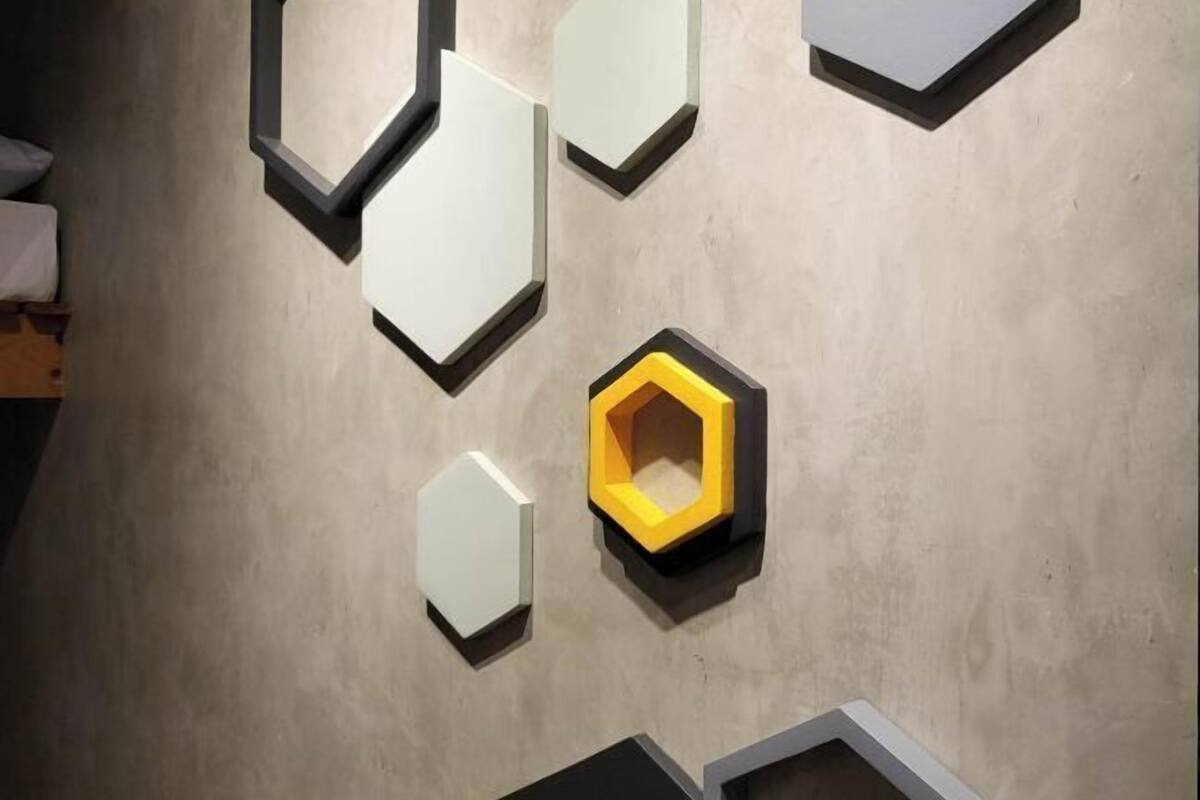 A wall with geometric wall art and a bed.