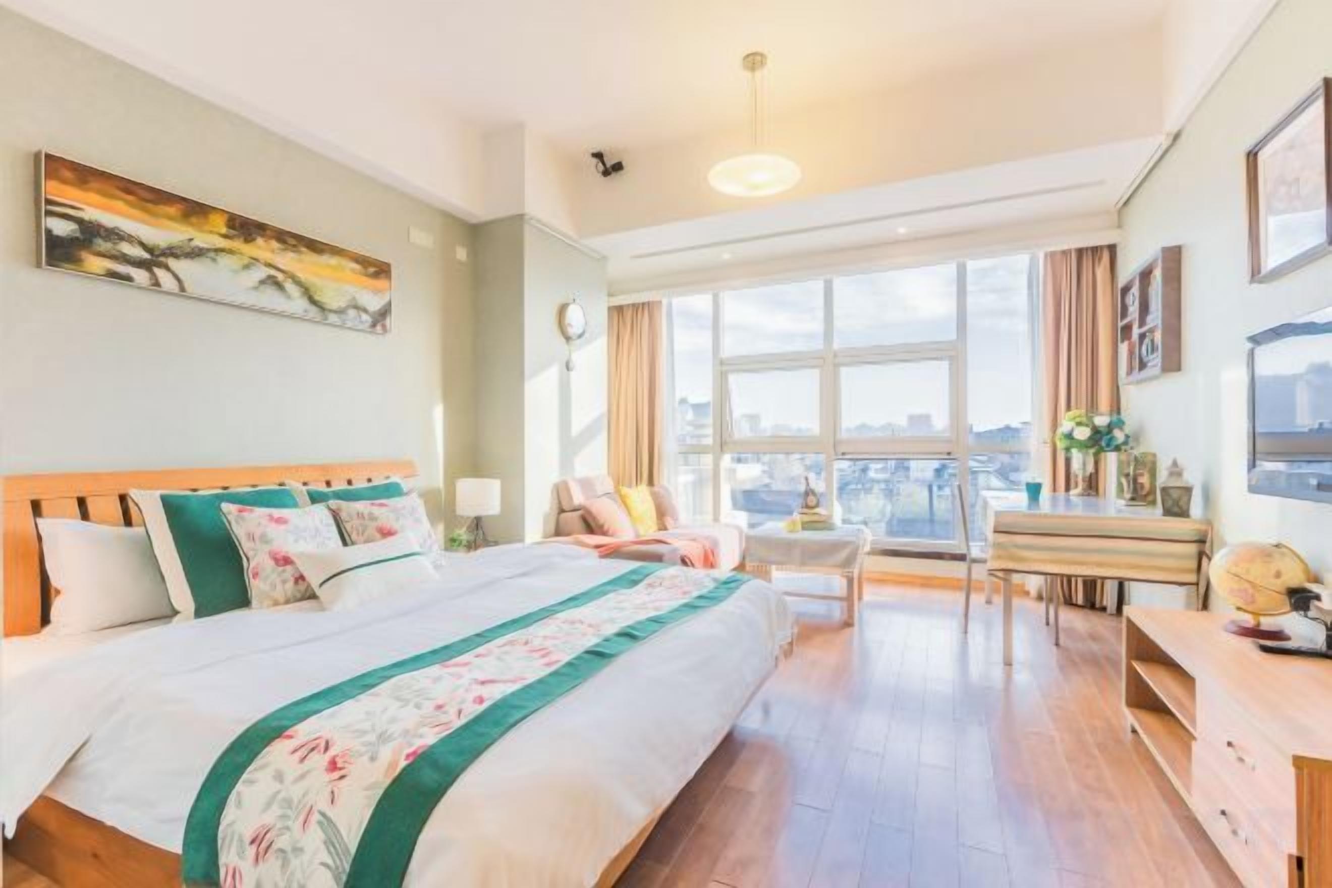 Una camera d'albergo con un letto grande, una scrivania, una sedia e vista sulla città da ampie finestre.
